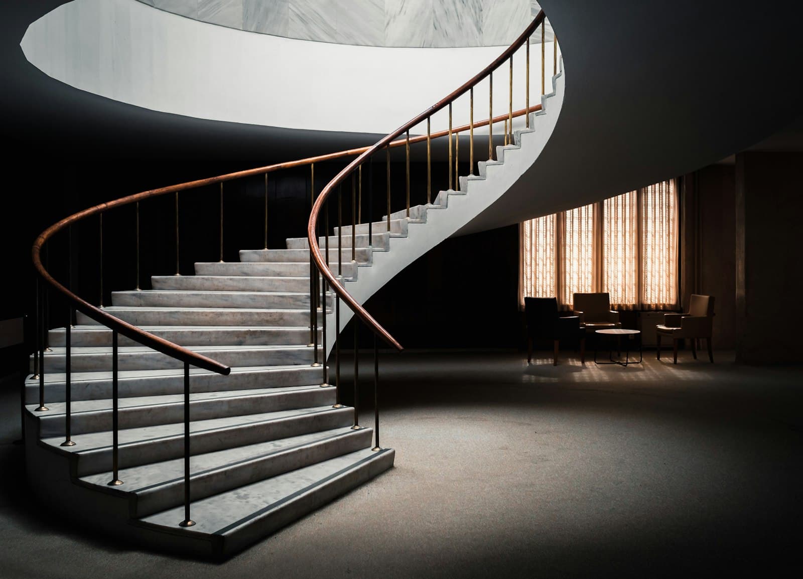 A curved staircase rising through a quiet interior